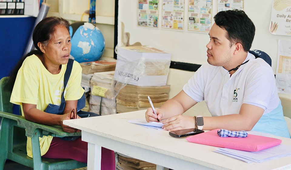 SEARCA's Kim Louisse Patagnan interviews a mother at Malbato Elementary School in Coron, Palawan.